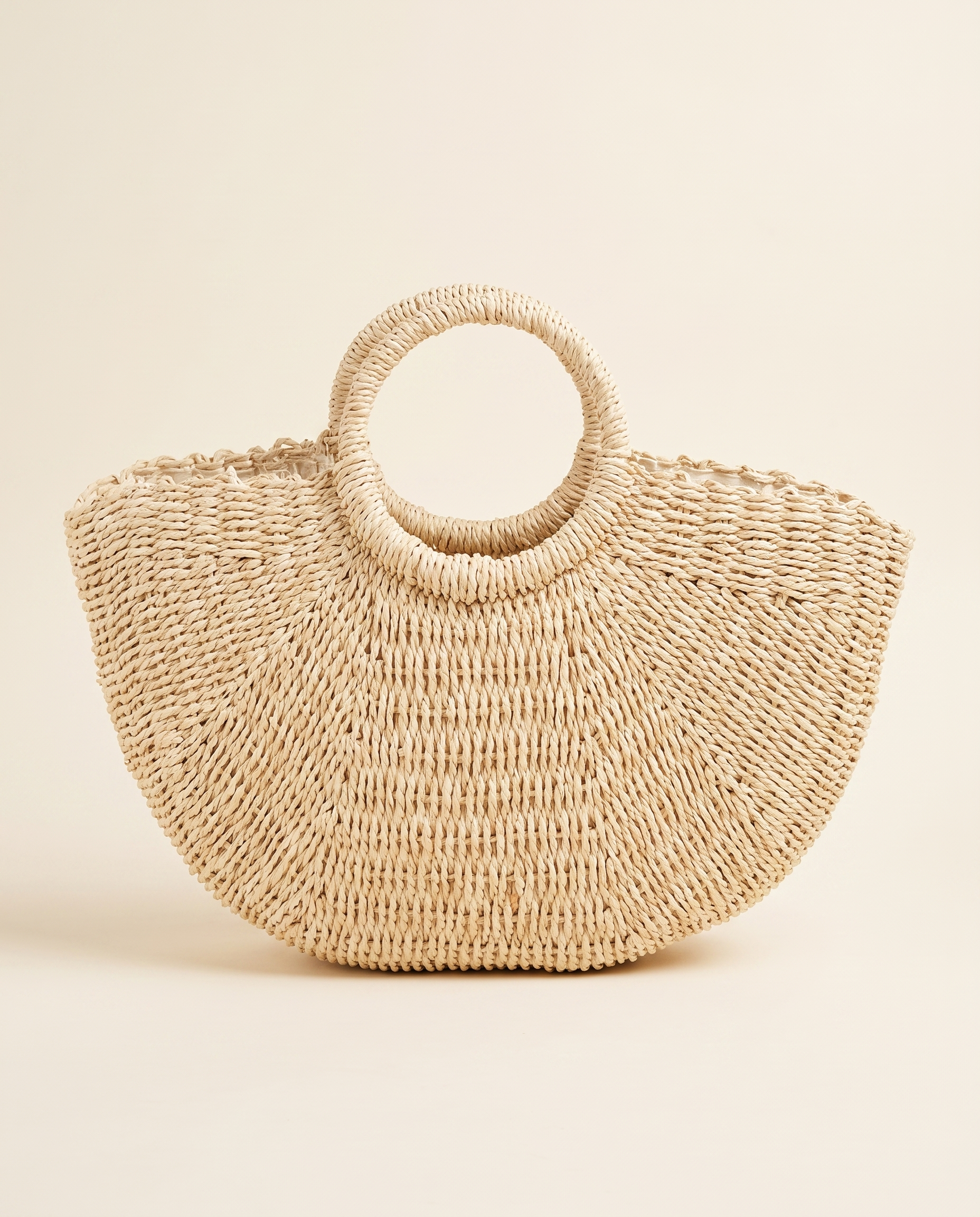 Half-Moon Straw Tote on a warm ivory studio background