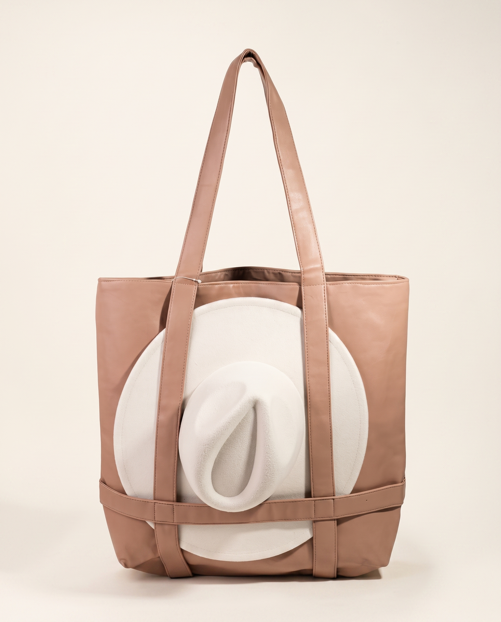 Hat-Carrier Leather Tote holding a wide-brim hat, on a warm ivory studio background