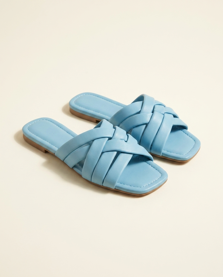 Light-blue woven-strap flat slide sandals on a warm ivory studio background